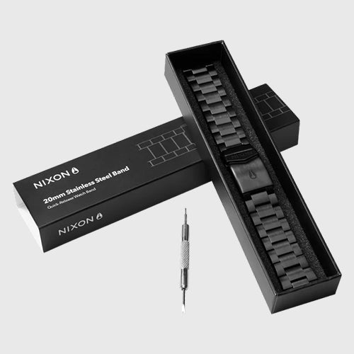 A black Nixon 20mm stainless steel quick-release watch band is displayed in its packaging with a spring bar tool.