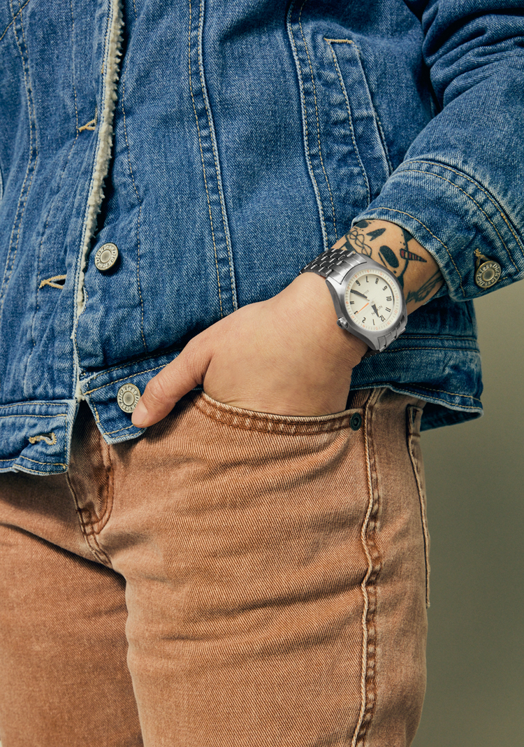 Man wearing a silver Nixon Echo 38 analog dress watch with his hand in his pocket